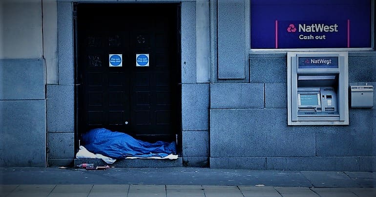 Homeless person sleeping near a cash point