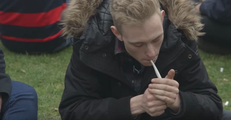 Man lighting a joint Camden Council's poster about smoking weed