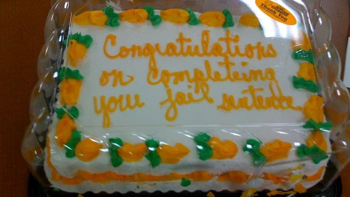 A celebration cake with "Congratulations on completeing your jail sentence" written on it in icing