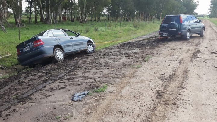 A car being towed off the edge of a muddy road