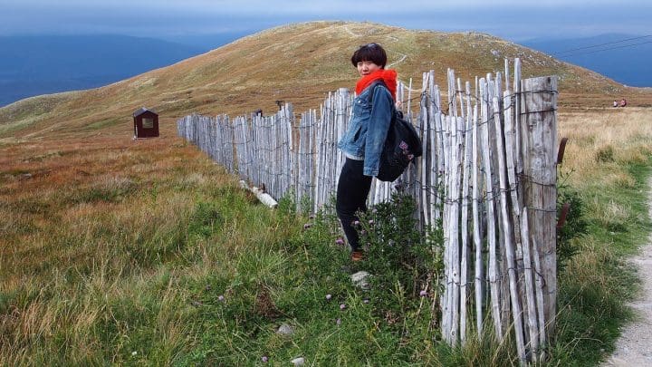 Tourist standing by a length of fence which stretches from nowhere to nowhere across a Scottish moor