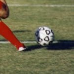 Football on a pitch with a player about to kick