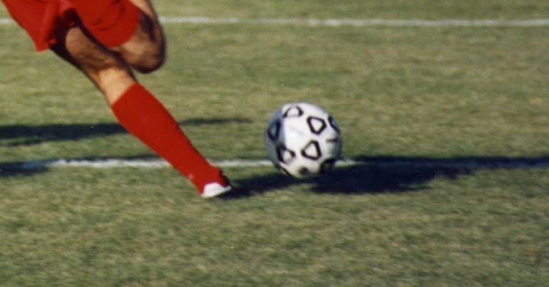 Football on a pitch with a player about to kick