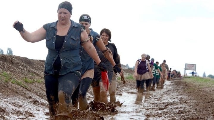 A line of people trudging along a muddy ditch