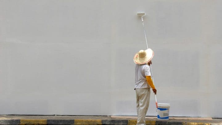 A person finishing painting a large wall white