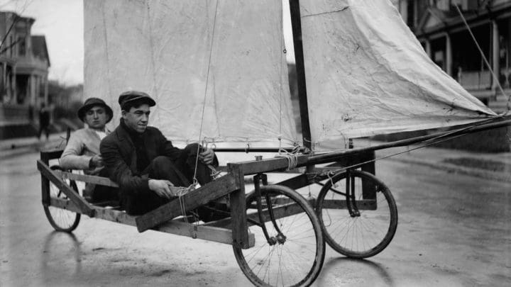 Two young men in a homemade land yacht / go-kart