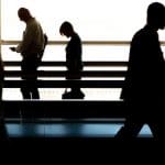 People walking along on the shadows with heads down