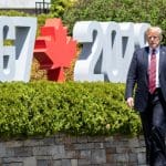 Trump walks in front of G7 sign in Montreal.