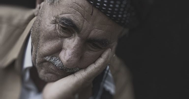 Elderly man with his head in his hand