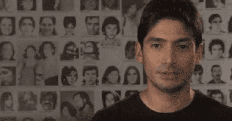 Man in front of photos of missing people
