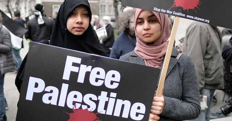 Women wearing hijabs and carrying 'Free Palestine" placards
