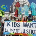 Children stand outside the US Capitol building holding a 'kids want climate justice' sign