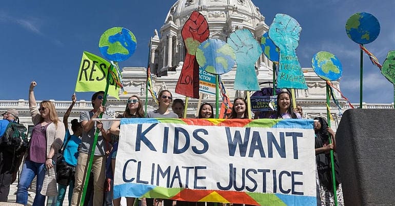 Children stand outside the US Capitol building holding a 'kids want climate justice' sign