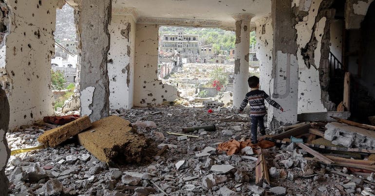 A Yemeni child running through a bombed building