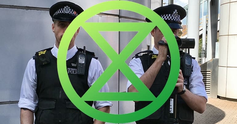 Cops with cameras with Extinction Rebellion logo
