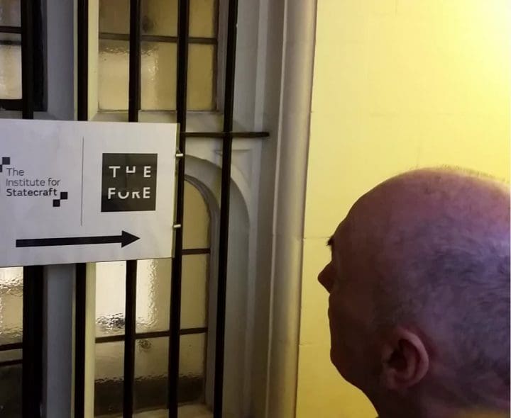 Chris Williams MP outside of IfS office in front of sign on 19 December 20187