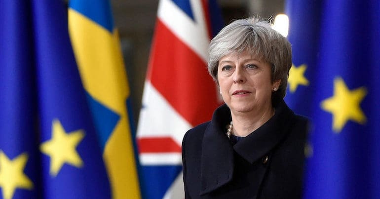 Theresa May surrounded by Union Jack and Brexit flags