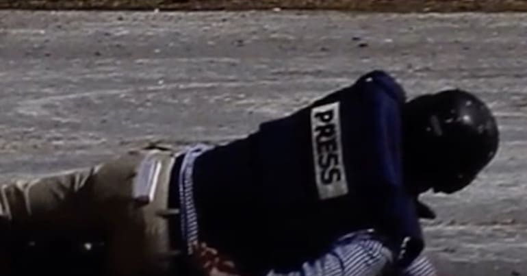 Person wearing a press jacket on the ground