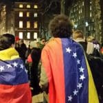 flags draped over Hands Off Venezuela protesters