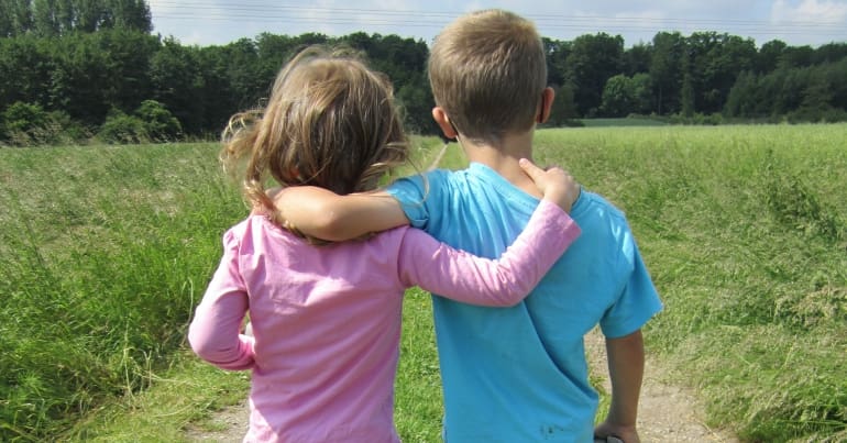 Two children walking with arms around each other