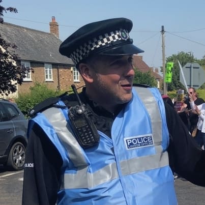 A police liaison officer talking to a papier mache Theresa May