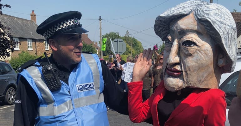 A police liaison officer talking to a papier mache Theresa May