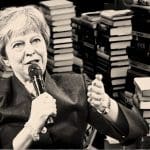 Theresa May in front of piles of books