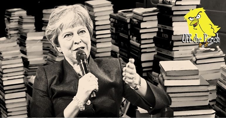 Theresa May in front of piles of books