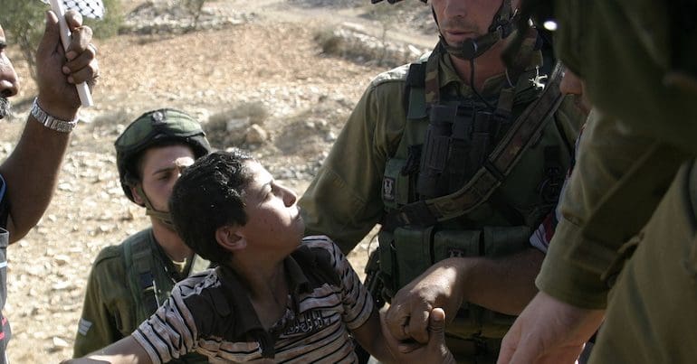 A Palestinian child surrounded by Israeli soldiers