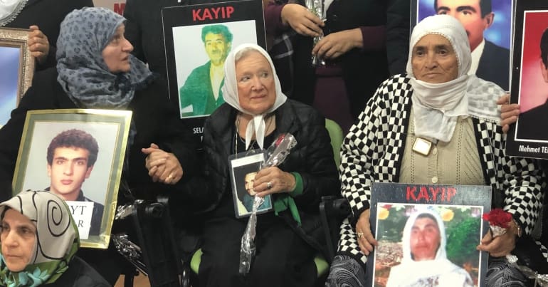 Mothers who have lost children holding hands at protest