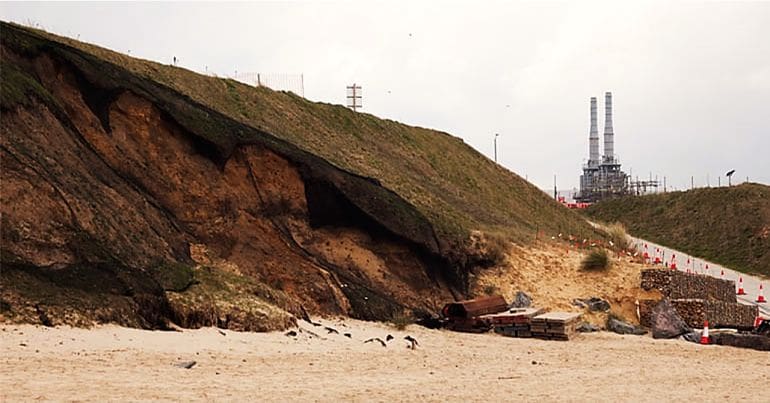 Netting on Bacton cliffs with gas terminal in the background