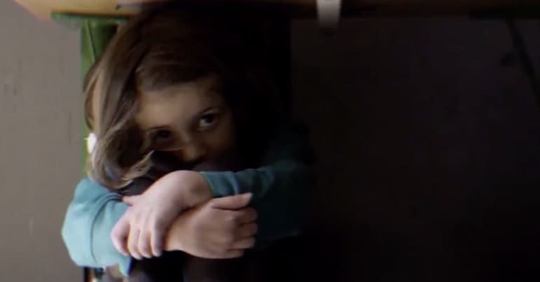 Child hiding under a desk in a shoot out drill