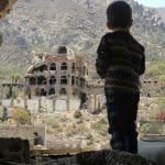 Young child looking out over bombed landscape in Yemen