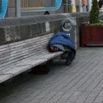 A photo of a homeless man in Dublin sleeping on a public bench.