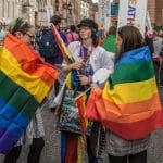 A photo of two people draped in the Pride flag during Dublin Pride