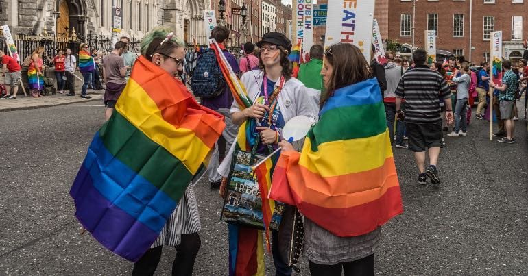 A photo of two people draped in the Pride flag during Dublin Pride