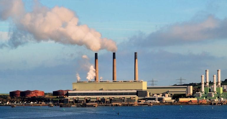 Photo of a power station and smoke coming from its stacks.