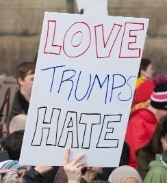 A picture of Donald Trump alongside protestors holding a banner that says "Love Trumps Hate".
