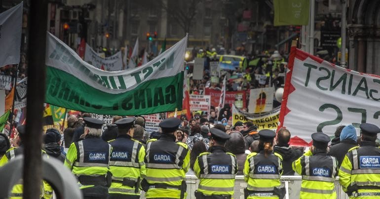 A photo of Gardaí, i.e., Irish police officers, watching a protest.