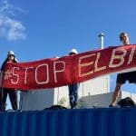 Protestors on top of Elbit roof with banner