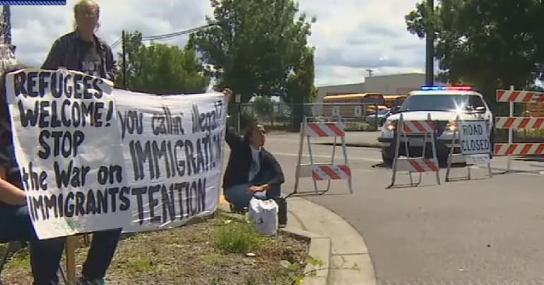 Protesters with sign saying "Refugees welcome. Stop the war on immigrants."