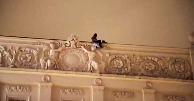 A man sitting on the edge of a roof with a second person next to him