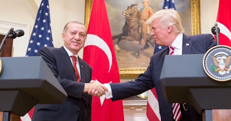 Donald Trump and Recep Tayyip Erdoğan shaking hands in front of US and Turkish flags