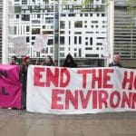 Activists holding up banners to protest against the Home Office's hostile environment policy