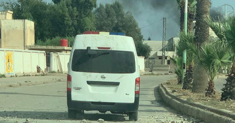An ambulance surrounded by destruction and smoke rising in Ras al Ayn on 20 October