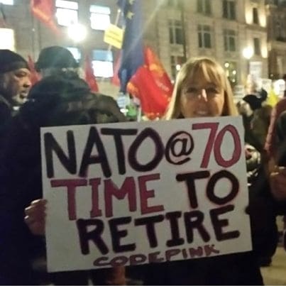 Medea Benjamin and fellow CODEPINK member holding anti-NATO placard