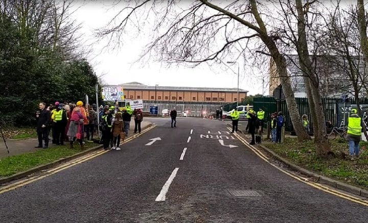Entrance to Belmarsh prison grounds with Yellow Vests and other demonstrators flanking both sides of the entrance