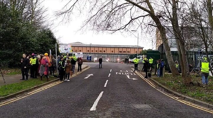 Entrance to Belmarsh prison grounds with Yellow Vests and other demonstrators flanking both sides of the entrance