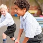 Two children in school uniform playing outdoors. This is in relation to trans kids and the DoE and gender