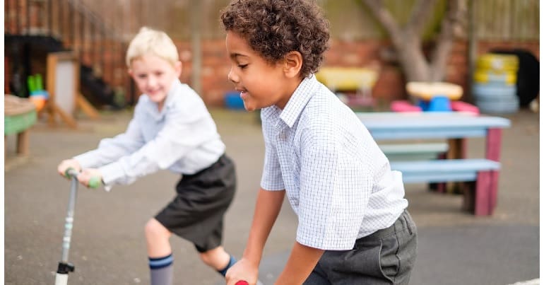 Two children in school uniform playing outdoors. This is in relation to trans kids and the DoE and gender